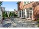 Stone patio offers seating with views of the manicured lawn, lush landscaping, white pergola, and large french doors at 1382 Murrays Loch Nw Pl, Kennesaw, GA 30152