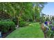 Manicured lawn of backyard is surrounded by lush landscaping, mature trees, and colorful flowers, offering a serene outdoor space at 1382 Murrays Loch Nw Pl, Kennesaw, GA 30152