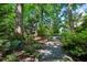 A stone and gravel garden path with a stone bench is surrounded by trees and greenery at 1382 Murrays Loch Nw Pl, Kennesaw, GA 30152