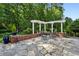 Spacious stone patio features a white pergola, red brick base, an outdoor dining set, and manicured landscaping at 1382 Murrays Loch Nw Pl, Kennesaw, GA 30152