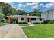 Lovely white-brick home featuring a driveway, manicured lawn, mature trees, and stylish carport at 4237 Rickenbacker Ne Way, Atlanta, GA 30342