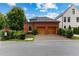 Picture of a brick home featuring a two-car garage with wooden doors, surrounded by greenery, and a clear blue sky at 185 Central Ave, Fayetteville, GA 30214