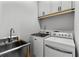Well-equipped laundry room featuring a utility sink, washer, dryer, and storage cabinets at 185 Central Ave, Fayetteville, GA 30214