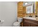 Powder room featuring natural wood paneling, a decorative mirror, and a classic vanity at 220 Hollyridge Dr, Roswell, GA 30076