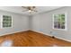 An empty bedroom has hardwood floors and two windows providing ample sunlight at 220 Hollyridge Dr, Roswell, GA 30076