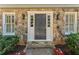 Inviting front entrance with a stone surround, classic black door, and decorative sconces at 220 Hollyridge Dr, Roswell, GA 30076