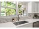 Kitchen sink with a window view of the backyard framed by white cabinetry and stone backsplash at 220 Hollyridge Dr, Roswell, GA 30076