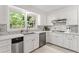 An open, white kitchen features stainless steel appliances and bright light from an exterior window at 220 Hollyridge Dr, Roswell, GA 30076