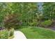 Lush backyard with green lawn, manicured garden beds, and mature trees providing a tranquil outdoor setting at 3088 Hidden Falls Dr, Buford, GA 30519