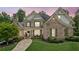 Beautiful brick home featuring manicured landscaping, stone chimney, and charming covered front porch with seating at 3088 Hidden Falls Dr, Buford, GA 30519