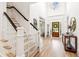 Bright foyer showcasing hardwood floors, staircase with dark railing, and wood paneled front door at 3088 Hidden Falls Dr, Buford, GA 30519
