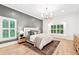 Bright main bedroom featuring hardwood floors, natural light, and a modern chandelier at 3088 Hidden Falls Dr, Buford, GA 30519