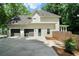 Rear exterior view of home featuring attached garage and rear entry, surrounded by mature trees and greenery at 4544 Cavallon Nw Way, Acworth, GA 30101