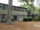 View of townhouse exterior featuring a wooded yard, covered patio, neutral colored siding, and many windows for natural light at 37 La Rue Nw Pl, Atlanta, GA 30327