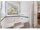 The white tile-surrounded bathtub features a garden window, and is next to a doorway leading to the bedroom at 1055 Avalon Dr, Lawrenceville, GA 30044