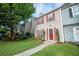 Inviting townhome with a lush green lawn, mature trees, and an appealing red front door and shutters at 3053 Shadow Walk Ln, Tucker, GA 30084
