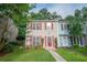 Charming townhome featuring a well-manicured lawn, mature trees, and inviting red door with matching window shutters at 3053 Shadow Walk Ln, Tucker, GA 30084
