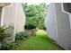 Side yard of a townhome featuring lush greenery, a wooden fence, and colorful flowers at 3053 Shadow Walk Ln, Tucker, GA 30084