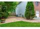Side yard with a stone pathway, flower bed, privacy fence, and lush greenery at 10980 Pinehigh Dr, Alpharetta, GA 30022
