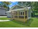 A cozy home showcasing a covered porch with dark railings and an inviting green lawn surrounded by green trees and a blue sky at 1675 White Oak Way, Decatur, GA 30032