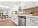 Beautiful modern kitchen with white cabinets, stainless steel appliances, farmhouse sink, and stylish backsplash, flowing into dining area at 1675 White Oak Way, Decatur, GA 30032
