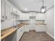 Updated kitchen featuring white cabinets, wood countertops, stainless steel faucet, and modern light fixture at 6486 Aquila Dr, Morrow, GA 30260