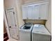 Convenient laundry room with modern washer, dryer, tile floor, and custom white cabinetry at 245 Fenwick Cir, Mcdonough, GA 30253