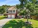Picturesque two-story house with a brick and siding exterior, framed by a large shade tree at 2740 Greymont Ct, Cumming, GA 30041