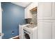 Modern laundry room with white cabinets, blue accent wall, and front load washer/dryer at 2740 Greymont Ct, Cumming, GA 30041