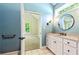 Bright bathroom featuring blue walls, round mirror, and a vanity with white cabinets at 115 Edgewater Way, Peachtree City, GA 30269