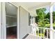 Inviting covered porch with white brick, wood floors and view to interior of home and landscaped front yard at 115 Edgewater Way, Peachtree City, GA 30269