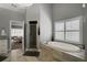 Bright bathroom features a modern tub, walk-in shower, and natural light from a window with white shutters at 2380 Tayside Nw Xing, Kennesaw, GA 30152