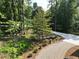 Curving gravel and cement driveway through a green yard and trees, adding to the home's curb appeal at 260 Lakemont Dr, Roswell, GA 30075