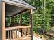 Comfortable covered porch with wooden rails overlooks the landscaped yard and wooded view at 260 Lakemont Dr, Roswell, GA 30075