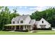 Inviting two-story farmhouse with a spacious covered porch and rocking chairs, nestled in a serene landscape at 2101 Thomas Rd, Canton, GA 30115