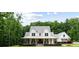 Stately two-story white farmhouse-style home featuring a covered porch with rocking chairs and lush landscaping at 2101 Thomas Rd, Canton, GA 30115