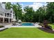 An in-ground pool is surrounded by ample patio space, lush greenery, and mature trees at 2101 Thomas Rd, Canton, GA 30115
