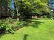 Lush backyard showcasing a spacious lawn, mature trees, and landscaped garden beds at 4094 Carlisle Pl, Stone Mountain, GA 30083