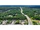An aerial view shows a neighborhood with a road nearby, surrounded by lush green trees and well-maintained lawns at 4003 Coachman Ct, Cumming, GA 30040