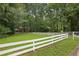 Spacious front yard view, showing a well-manicured lawn, white picket fence and tree line at 980 Hightower Trl, Sandy Springs, GA 30350
