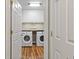 Bright laundry room with wood floors features a stacked washer and dryer and white cabinets at 722 Ivory Trl, Woodstock, GA 30188