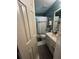 Small, blue-green bathroom with a standard vanity and bathtub with white, patterned shower curtain at 974 Bloomfield Dr, Lawrenceville, GA 30044