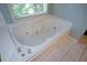White tub with jacuzzi jets, faucet handles, and a window providing natural light and a view at 1464 Chatsworth Trace, Lawrenceville, GA 30044