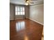 Bedroom showcasing hardwood floors, a ceiling fan, and a large window allowing for an abundance of light at 1464 Chatsworth Trace, Lawrenceville, GA 30044