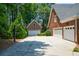 Three-car garage with driveway, basketball hoop, and lush greenery at 1464 Chatsworth Trace, Lawrenceville, GA 30044