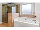 Bathroom featuring corner soaking tub with window and glass enclosed shower with brown tiling at 162 Aylesbury Blvd, Mcdonough, GA 30252