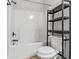 Bright bathroom featuring a toilet, shower-tub combo and storage shelf at 162 Aylesbury Blvd, Mcdonough, GA 30252