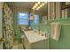 Bathroom with green tiling, floral wallpaper, a large sink, a window, and decorative lighting at 1349 Springwood Nw Dr, Conyers, GA 30012
