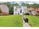 View of the front of the townhome with a large lawn, manicured greenery, and a classic white painted brick facade at 208 Hembree Park Ter, Roswell, GA 30076