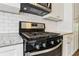 Close-up of a modern gas stove, granite countertops, and white subway tile backsplash in a well-lit kitchen at 208 Hembree Park Ter, Roswell, GA 30076